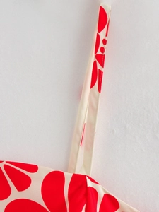 Detailed macro view of delicate red floral print on linen fabric with thin shoulder strap