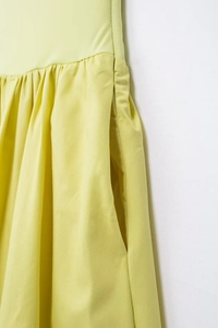 Détail de la taille d'une robe jaune clair avec poche latérale cachée et tissu plissé