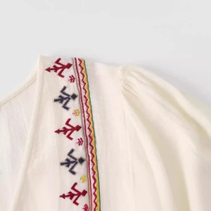 Embroidered neckline detail of an off-white cotton summer dress with ethnic patterns