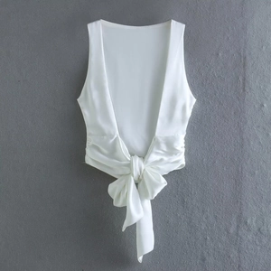 Close-up of white satin backless top featuring a large bow tie knot at the hemline