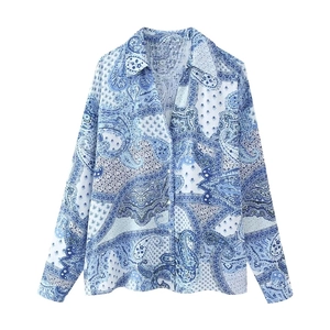 Detail view of paisley print blouse with classic collar and front buttons on blue fabric