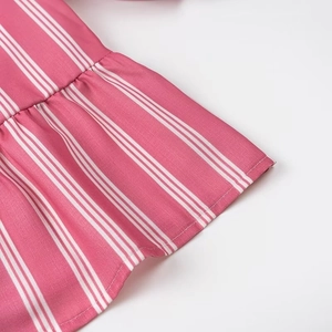 Detailed close-up of rose pink striped fabric featuring delicate ruffle edge stitching