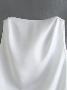 Detailed close-up of white backless silk-textured top showing smooth satin fabric texture