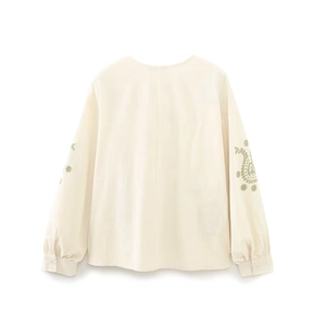 Vue détaillée de la broderie paisley vert clair sur les manches de la chemise en coton crème