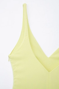 Détail d'une robe jaune clair à col en V avec fines bretelles et zip invisible latéral
