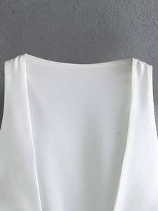 Detail view of white backless silk-textured top neckline on dark grey textured background