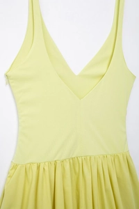 Détail du décolleté en V profond et des plis sur la robe d'été jaune sans manches
