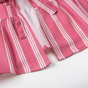 Detail of pink and white striped fabric featuring a tie string and layered ruffle hemline