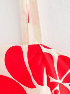 Detailed close-up of the red floral print fabric and strap stitching on the summer dress