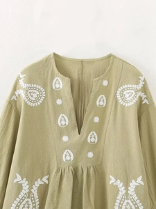 Détail de broderie bohème blanche sur chemisier en coton lin vert clair à col en V