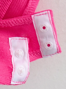 Macro detail of the reinforced crotch with white snap buttons on pink ribbed baby romper