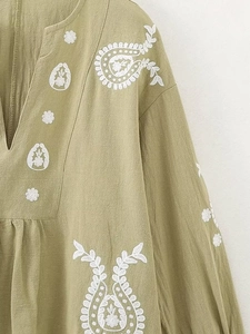 Détail du haut vert en lin avec col en V et broderie florale paisley blanche