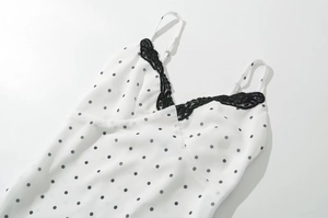 Dettaglio della stampa a pois neri su tessuto bianco con bordo in pizzo sul décolleté