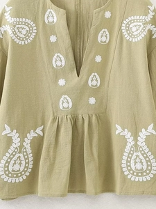 Détail du haut bohème vert clair avec broderie paisley blanche et décolleté en V profond