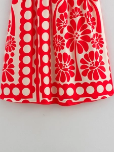 Detailed view of the red and white floral print hem on a flowing maxi dress skirt