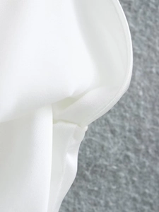 Detailed view of white silk fabric showing refined curved seams and high-quality stitching