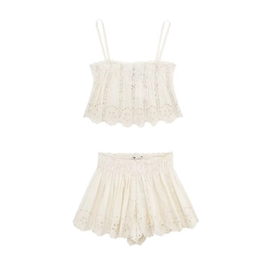 Detail of white embroidered two-piece set featuring hollow lace patterns and wavy edges