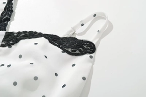 Dettaglio del bordo in pizzo nero su abito bianco a pois con spalline sottili regolate