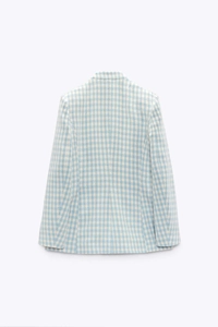 Detail showing the light blue houndstooth texture and tailored back seam of the blazer