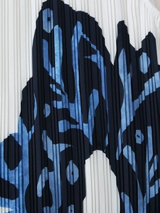 Macro shot of vertical pleated fabric with abstract blue and black print on white background