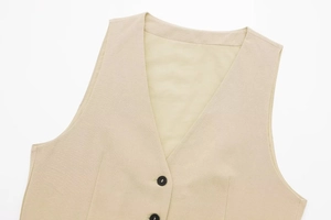 Detailed close-up of beige linen vest with black buttons and refined stitching texture