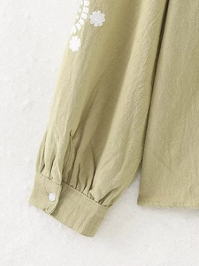 Vue détaillée de la broderie florale blanche sur la manche d'une chemise en lin vert
