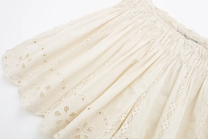 Detail of cream eyelet embroidery and wavy lace trim on lightweight summer fabric