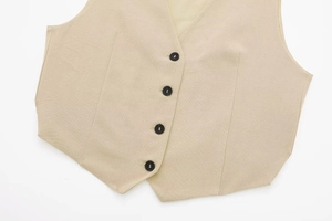 Detailed macro view of beige linen vest with four black buttons and fabric texture