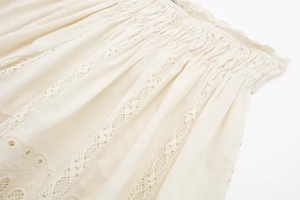 Detail of bohemian cream cotton set featuring diamond lace inserts and floral embroidery
