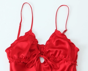 Detail of red satin camisole with delicate ruffle trim and decorative front lace-up bow