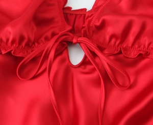 Close-up of red satin midi dress featuring a bow tie detail and ruffled neckline