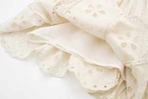 Detail of white embroidery broderie anglaise fabric with scalloped edge and floral pattern