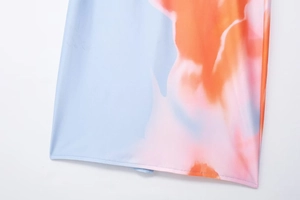 Détail de l'ourlet d'une robe d'été bleu clair avec des motifs tie-dye orange et roses