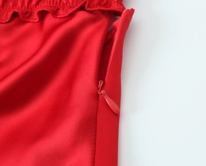 Close-up of the red satin midi dress showing the side invisible zipper and ruffle trim
