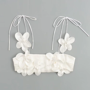 Detail of white cropped top with 3D floral decorations and adjustable tie-straps