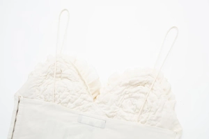 Vue détaillée du haut bustier blanc crème avec de fines bretelles et des agrafes latérales