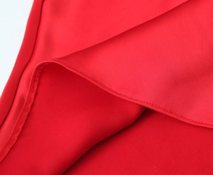 Macro shot of red satin fabric showing fine stitching and glossy silk texture details