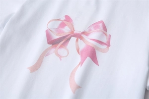 Détail de l'imprimé nœud rose satiné sur un t-shirt blanc à manches courtes de qualité