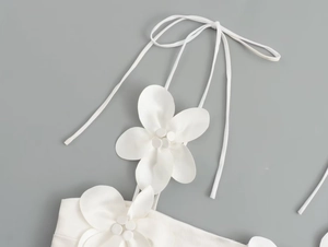 Detailed close-up of white 3D satin flower applique and thin straps on camisole top