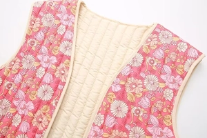 Détail d'un gilet matelassé rose à fleurs avec imprimés marguerites et coutures verticales