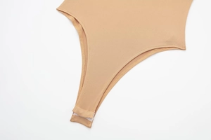 Detailed view of the snap-button closure on the crotch of the apricot bodysuit