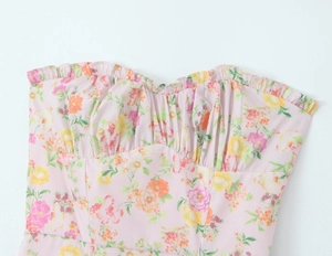 Détail d'un haut bandeau à fleurs avec buste froncé et tissu en coton rose à volants