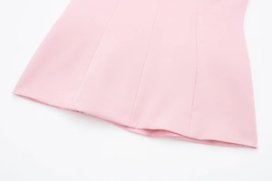 Détail de la texture du tissu satiné rose clair et des coutures soignées sur l'ourlet