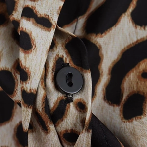Détail d'un bouton en résine noire et d'une boutonnière sur tissu imprimé léopard