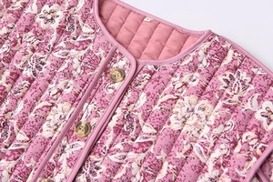 Vue détaillée du tissu matelassé à fleurs roses et bouton ambre sur la veste