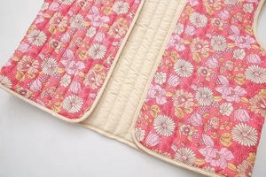 Détail de la veste matelassée en coton fleuri montrant les coutures et l'ourlet arrondi