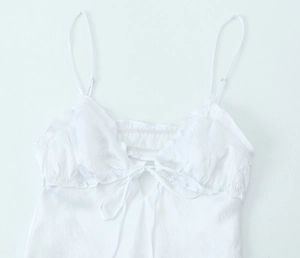 Detail of white satin camisole featuring delicate ruffles and front tie-up closure