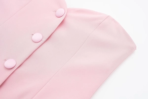 Détail du tissu satiné rose avec trois boutons ronds recouverts sur le vêtement
