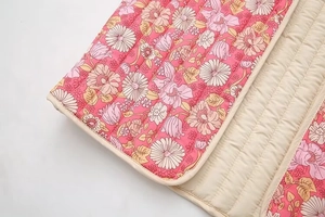 Détail du tissu en coton matelassé avec motifs floraux roses et coutures régulières