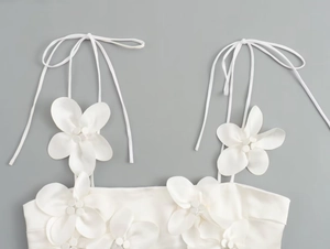 Detailed view of white satin top featuring 3D flowers and delicate bead accents